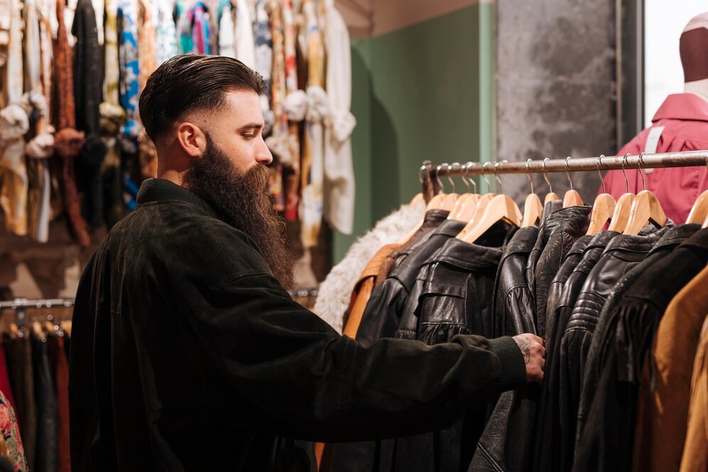 man organising leather jacket on wooden hanger